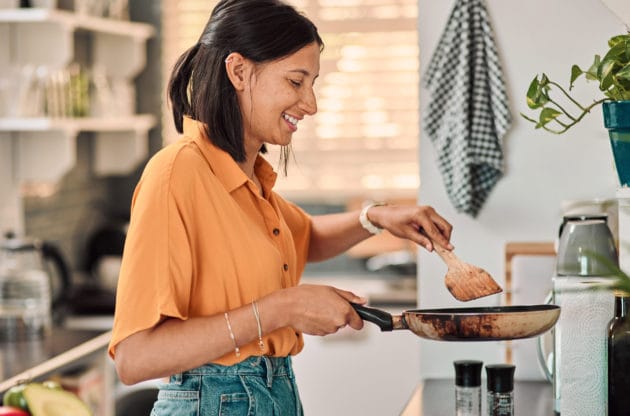 Shot of a happy young woman preparing a healthy meal at home.