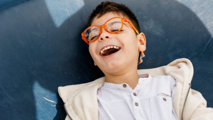 Child with multi-disability, quadriplegic medical box play lying on big swing in a city park. adapted park. Relaxed and smiling.