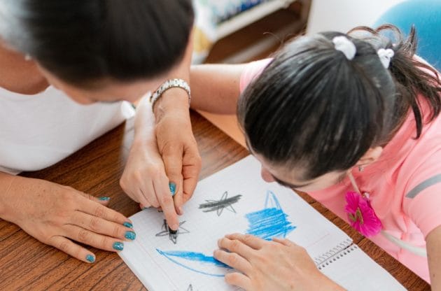 A adult coloring with a caregiver.