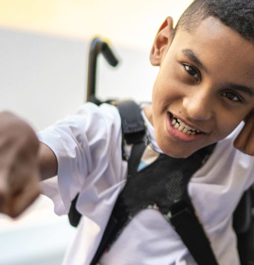 A boy smiling in a wheelchair.