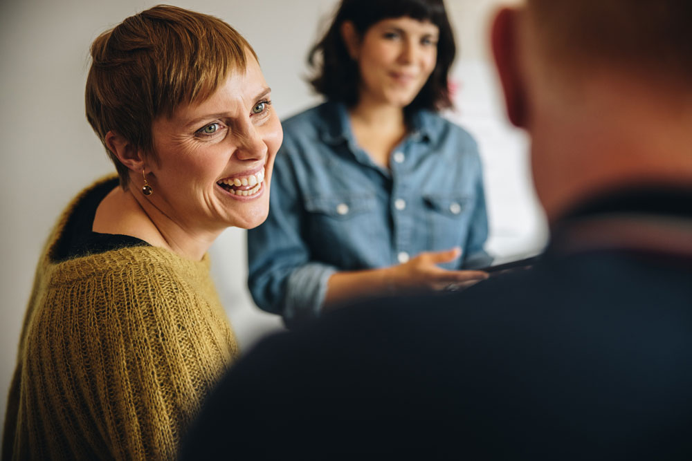 A woman is having a conversation with two coworkers.