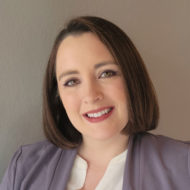 Portrait of April Foster, a woman with short brown hair in a purple suit jacket and white blouse.