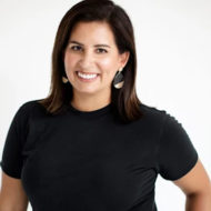 Portrait of Melanie Fountaine, a woman smiling in a black t-shirt with shoulder-length brown hair.