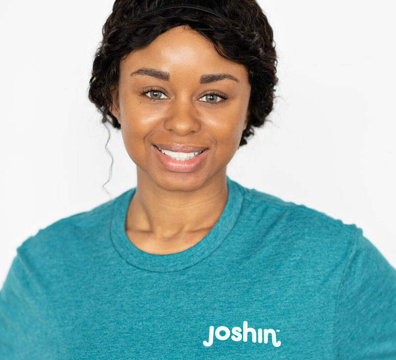 Portrait of Dre Soper, a smiling woman with black hair and a teal Joshin t-shirt.