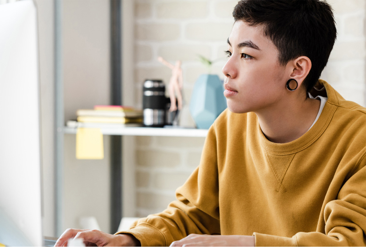 Young person in casual attire working on their computer in an office