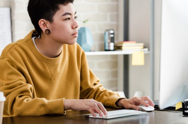 Young person in casual attire working on their computer in an office